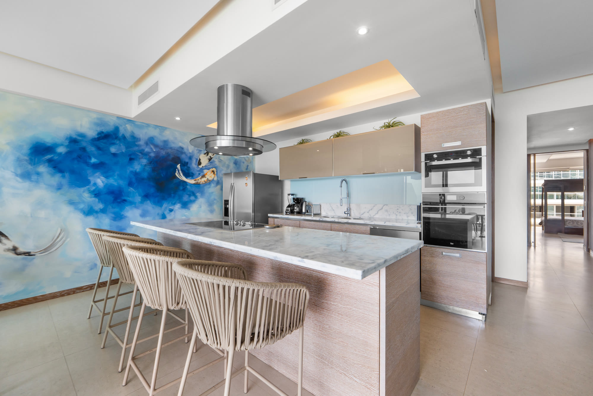 Cocina con isla de mármol y mural de kois